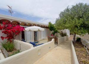 a house with a fence and an umbrella at Es Garrovers - Formentera Break in Sant Ferran de Ses Roques