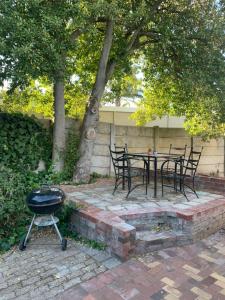 a bbq and a table with chairs and a grill at Little Elm Cottage in Cape Town