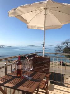 una mesa de picnic con copas de vino y una sombrilla en Apartman Voch, en Zambratija