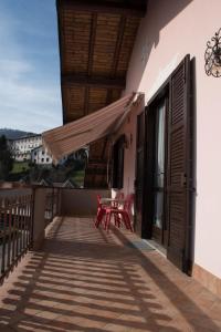 uma varanda com 2 cadeiras vermelhas e uma mesa em casa vacanze al paesello em Orezzo