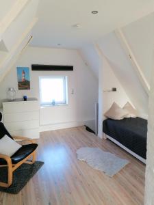 a bedroom with a bed and a chair in a attic at Ferienhaus Mia, Urlaub mit Hund, eingezäunter Garten, Friedrichskoog-Spitze in Friedrichskoog