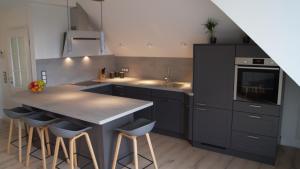 a kitchen with black cabinets and a counter with stools at Ferienwohnung Lohf in Handewitt
