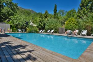 a swimming pool with a wooden deck and chairs at Camping Les Cent Chênes in Saint-Jeannet