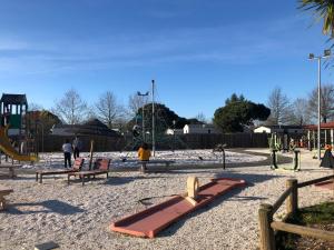 a playground with benches and a slide in the sand at La réserve 92 in Gastes