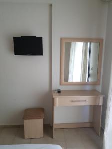 a bedroom with a dresser with a mirror and a television at Lemon Flowers Apartments in Nea Skioni