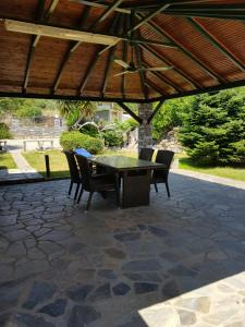 a patio with a table and chairs under a wooden roof at Lemon Flowers Apartments in Nea Skioni
