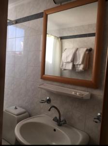 a bathroom with a sink and a mirror and a toilet at PHILOXENIA PENSION in Ermioni