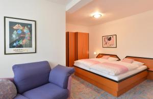 a bedroom with a bed and a blue chair at Rhön-Hotel Sonnenhof - in Poppenhausen