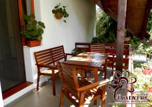 a wooden table and chairs on a porch at Casa din Parc in Covasna