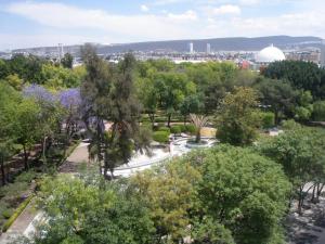 einen Park mit Bäumen und einer Kuppel in der Ferne in der Unterkunft Hotel Amberes in Querétaro