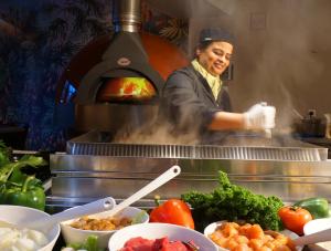 a woman cooking in a kitchen with a pizza oven at Hotel Schaepkens van St Fijt in Valkenburg