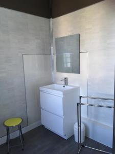 a white bathroom with a sink and a stool at Le Narval in Saint-Jean-de-Monts