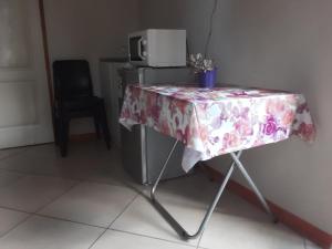 a table with a flowered table cloth on it next to a refrigerator at Rosy Palm Sunrise in Upington
