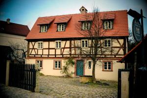 a large house with a red roof on a cobblestone street at Dom Tkacza in Pieszyce