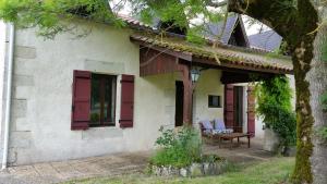 Casa blanca con persianas rojas y patio en Gîte Tissendie, en Bourg-de-Visa