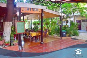 ein Restaurant mit Tisch und Stühlen und ein Schild in der Unterkunft Hotel y Apartments Los Cisneros in Managua