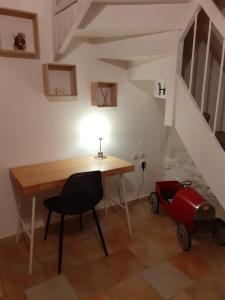una habitación con una mesa, una silla y una maleta en La petite Oustal, en Marseillette