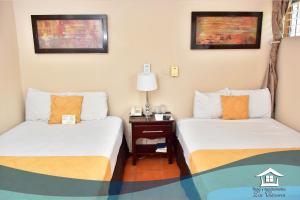 Habitación con 2 camas y mesa con lámpara. en Hotel y Apartments Los Cisneros en Managua