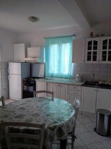 uma cozinha com uma mesa e uma cozinha com armários brancos em Apartmani Nedjeljka em Viganj