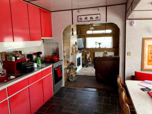 a kitchen with red cabinets and a living room at Vintage, Circus Holiday Home in Mablethorpe