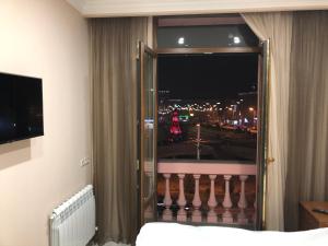 a bedroom with a window with a view of a city at Квартира около станции метро с балконами in Yerevan