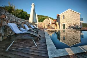 a pool with chairs and an umbrella next to a wall at Klinci Village Resort in Lustica