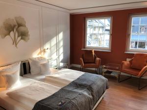 a bedroom with a large bed and two chairs at Hofgut Georgenthal in Burg Hohenstein