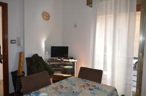 sala de estar con mesa, sillas y TV en casa Trieste en Scoglitti