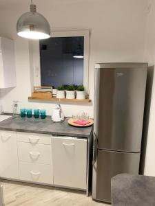 a kitchen with a stainless steel refrigerator and white cabinets at Apartament Sucharskiego in Toruń