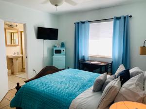 sypialnia z łóżkiem z niebieskimi zasłonami i oknem w obiekcie Blue House Miami w Miami Beach
