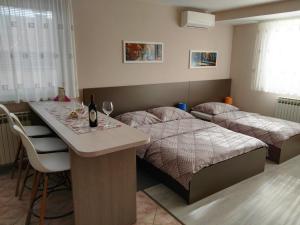 a bedroom with two beds and a table with wine glasses at Apartmani Janjic in Banja Luka