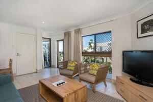 a living room filled with furniture and a tv at Bayview Beachfront Apartments in Byron Bay