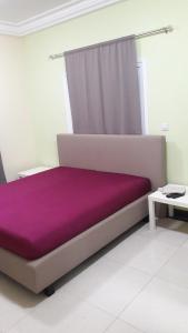 - une chambre avec un lit violet et un rideau dans l'établissement Residence 21, à Kololi