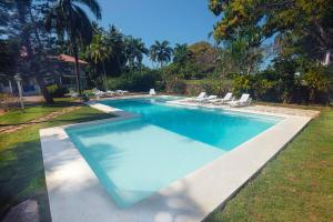 a swimming pool with lounge chairs in a yard at El Pelicano Apart-Hotel in Las Galeras