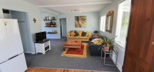 a living room with a couch and a tv at Quintessential kiwi bach in Oneroa