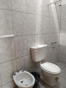 a white bathroom with a toilet and a sink at Hospedaje Las Tinajas in Molinos