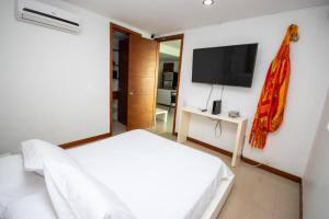 1 dormitorio con 1 cama blanca y TV de pantalla plana en Excelente Apartamento Palmetto con vista al mar en Cartagena de Indias