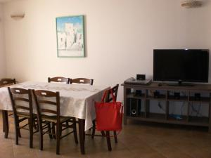 uma sala de jantar com uma mesa com cadeiras e uma televisão em Studio Flat em Salve