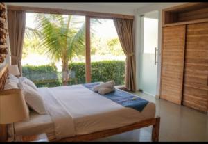 a bedroom with a bed and a large window at D'sawah Villa in Tanah Lot