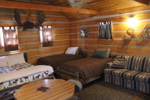 a log cabin with two beds and a couch at Sugar Loaf Lodge & Cabins in Anaconda
