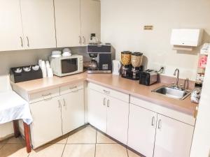 a kitchen with white cabinets and a microwave at Hotel 7 Inn Vienna in Vienna