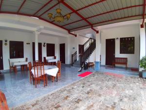 ein Wohnzimmer mit einem Tisch, Stühlen und einer Decke in der Unterkunft Radha Tourist Home in Polonnaruwa