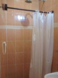 a shower with a white shower curtain in a bathroom at Posada Olmeca in Playa del Carmen