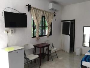 a room with a table and chairs and a television at Posada Olmeca in Playa del Carmen