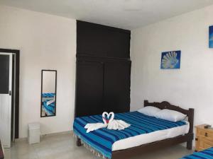 a bedroom with a bed with a towel animal on it at Posada Olmeca in Playa del Carmen