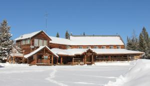 una baita di tronchi nella neve con neve di Sugar Loaf Lodge & Cabins ad Anaconda