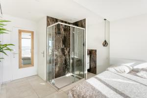 - une douche en verre dans une chambre avec un lit dans l'établissement Bali Heliopolis naturiste, au Cap d'Agde