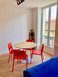 uma sala de estar com uma mesa e cadeiras vermelhas em Immeuble de charme La Tronche em La Tronche