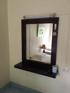 a mirror on a wall with a bed in a room at J-2 Court in Songkhla