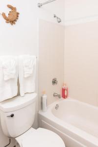 a white bathroom with a toilet and a bath tub at ENVITAE Luxury Sky Loft Indoor Pool & Gym in Chicago